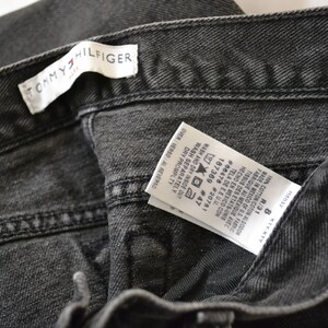 May include: A black Tommy Hilfiger jeans label with care instructions and size information. The label reads "1% COTTON COTON ALGODON", "MADE IN MEXICO OF US FABRIC", "FABRIQUE AU MEXIQUE AVEC TISSUS DES ETATS-UNIS", "HECHO EN MEXICO CON TELA DE EEUU.", "#66476 #20781", "187369 #47", "WASH AND DRY INSIDE OUT", "WASH SEPARATELY", "DRY PROMPTLY", "OVER VERSO AL REVERSO", "KTYKTY", "R/31", "8".