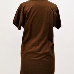 May include: A brown t-shirt dress with short sleeves, shown on a mannequin. The dress features a scoop neckline and a straight, relaxed fit. The fabric looks soft and solid-coloured, ideal for casual wear. The dress is a medium length.