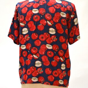 May include: A navy blue short-sleeved shirt with a red apple print.