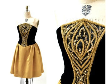 May include: A strapless dress with a black velvet bodice and a gold satin skirt. The bodice is embellished with gold sequins and beading in a geometric pattern.
