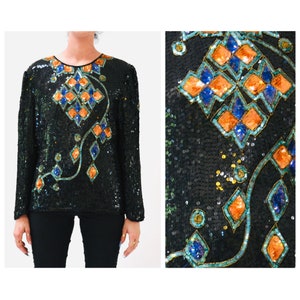 Può includere: Un top nero a maniche lunghe con paillettes e un design geometrico in arancione, blu e verde.