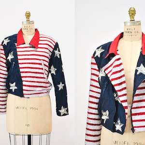 May include: A cropped, blue and red sequined jacket with a zipper closure and a star pattern. The jacket is on a white mannequin. The jacket has the text "MODEL 1994" on the front.