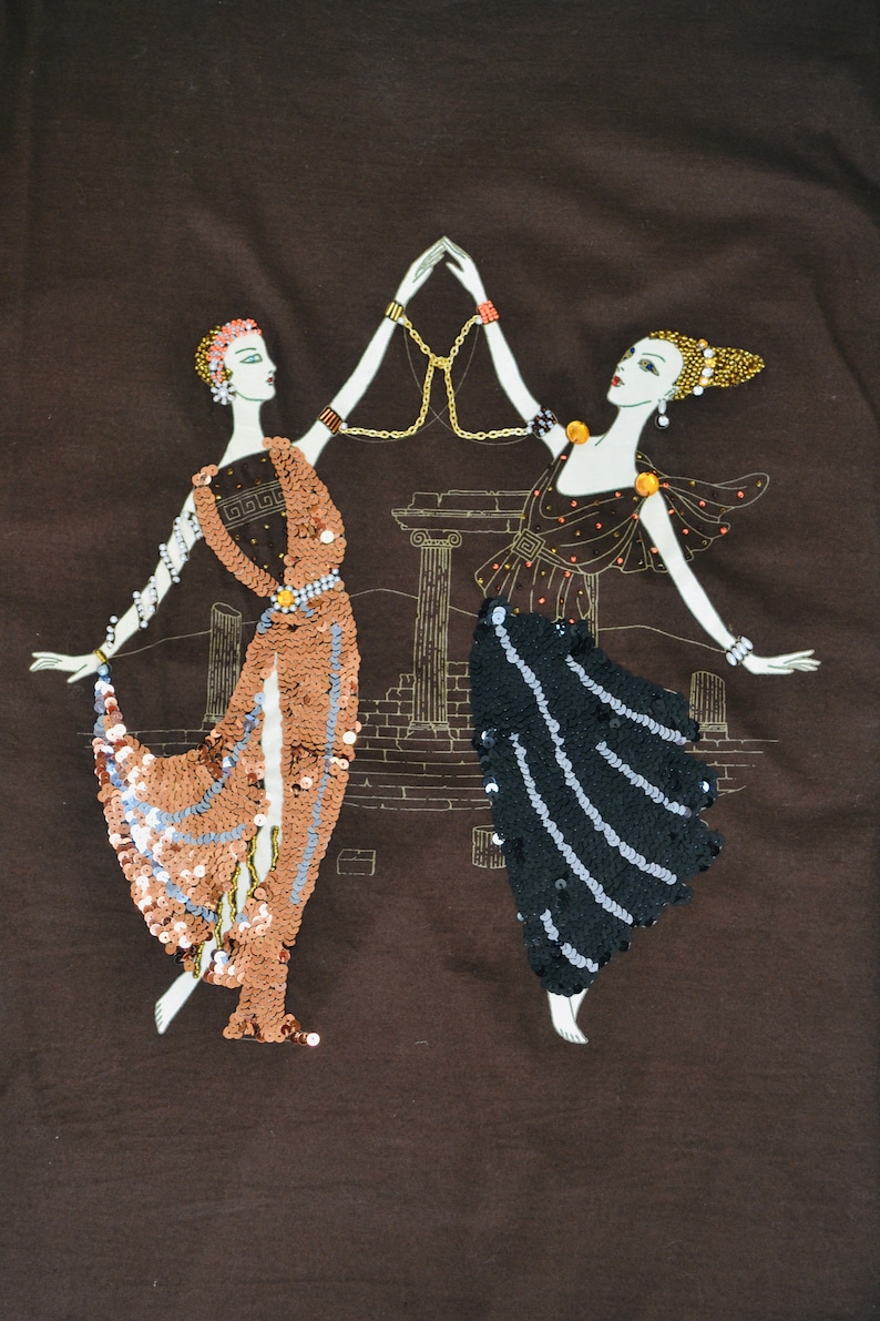 May include: Brown fabric featuring an embroidered design of two figures in flowing gowns, decorated with sequins and jewellery. They are holding hands, with a gold chain between them. A classical architectural backdrop is in the background.