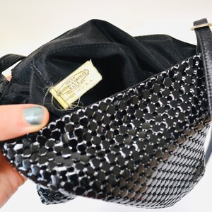 May include: Black mesh purse with a gold chain strap and a label that reads "Made in USA" by "Whitting & Davis, Inc."