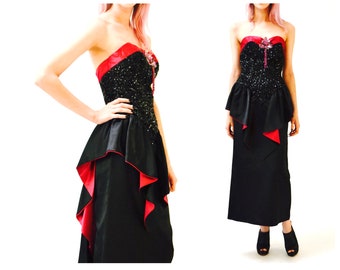 May include: A black strapless gown with a sequined bodice and a red satin trim. The skirt has a layered design with a ruffled hem.