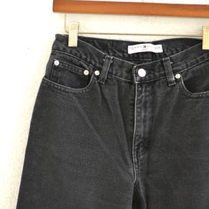 May include: Black denim jeans with a Tommy Hilfiger label. The jeans have a classic five-pocket style and a straight leg.