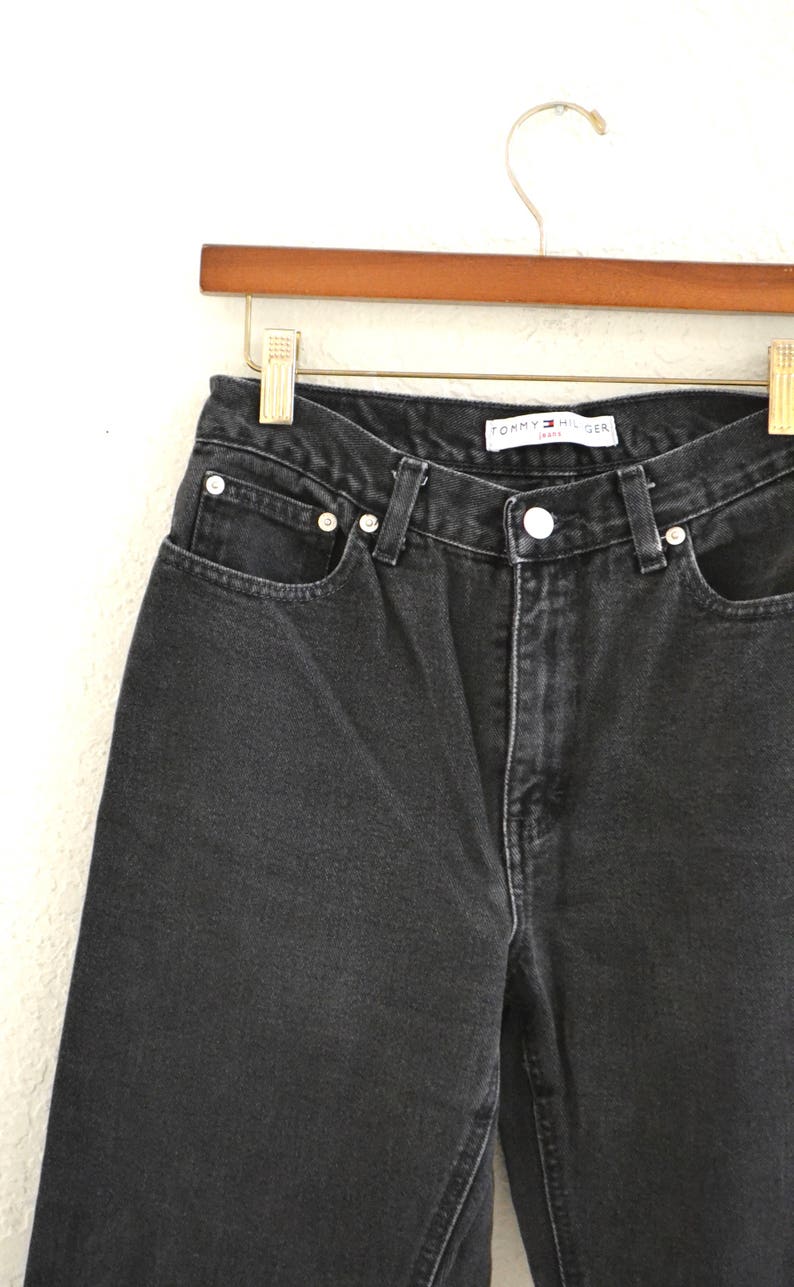 May include: Black denim jeans with a Tommy Hilfiger label. The jeans have a classic five-pocket style and a straight leg.