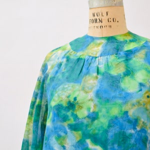May include: A blue and green floral print blouse with long sleeves and a round neckline.