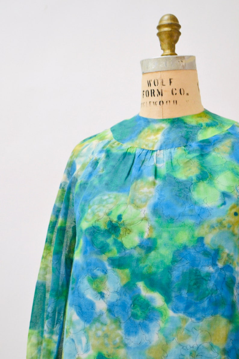 May include: A blue and green floral print blouse with long sleeves and a round neckline.