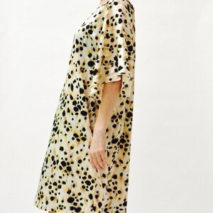 May include: A beige and black animal print dress with a loose fit and 3/4 sleeves.