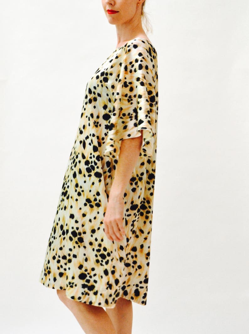 May include: A beige and black animal print dress with a loose fit and 3/4 sleeves.