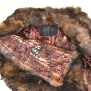 May include: A brown fur vest with a brown and white patterned lining. The vest has a label that says "La Fox" and a tag that says "L.A.F."