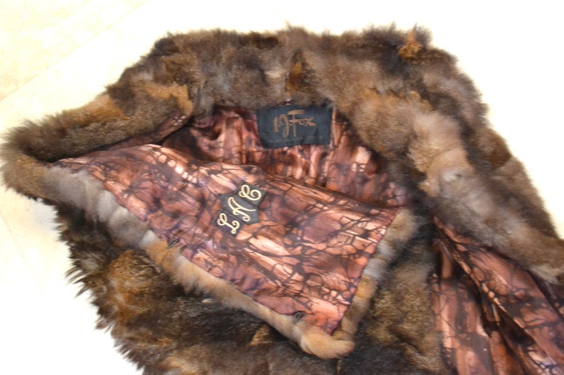 May include: A brown fur vest with a brown and white patterned lining. The vest has a label that says "La Fox" and a tag that says "L.A.F."