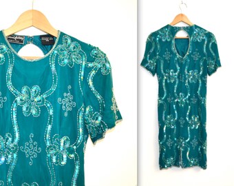 May include: Teal sequined dress with a keyhole back and short sleeves. The dress is covered in iridescent sequins in a floral pattern.