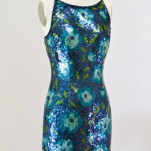 May include: A sleeveless sequined dress with a floral pattern in shades of blue and green.