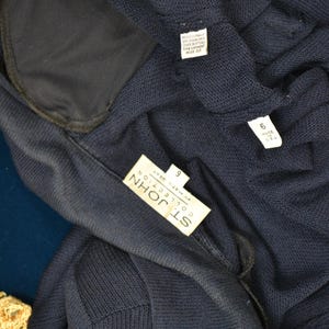 May include: A navy blue knit cardigan with a label that reads "St. John Collection by Marie Gray" and a size tag that reads "9".