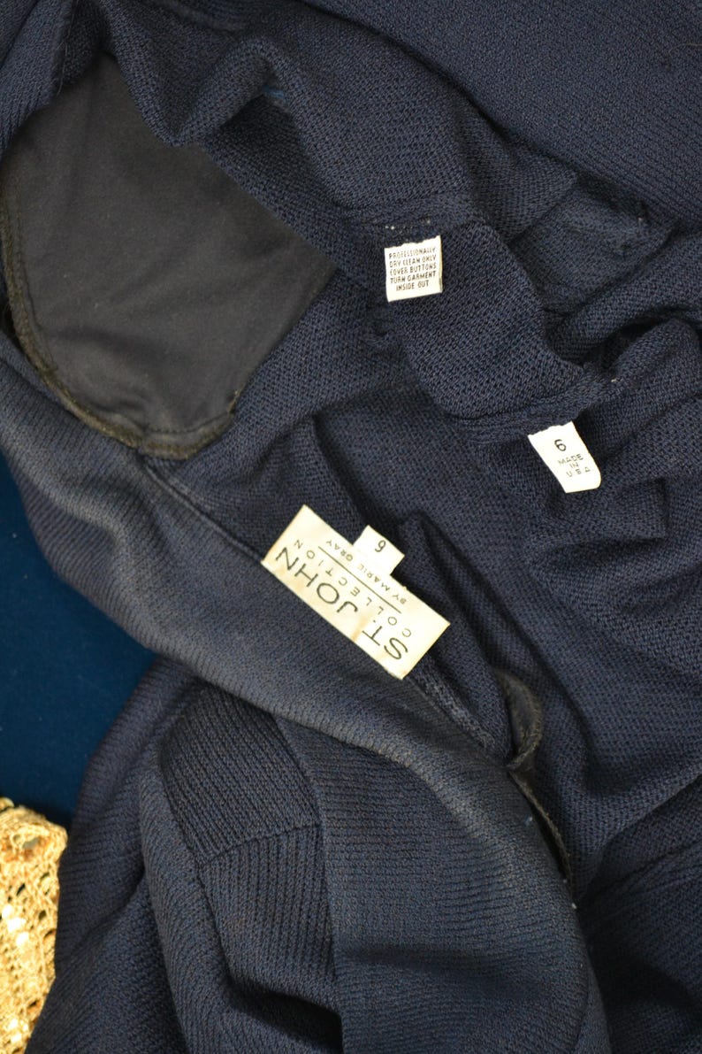 May include: A navy blue knit cardigan with a label that reads "St. John Collection by Marie Gray" and a size tag that reads "9".