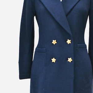 May include: A navy blue knitted blazer with a double breasted closure and gold star buttons.