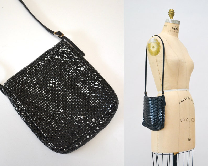 May include: A black chainmail shoulder bag with a long adjustable strap. The bag is made of small metal rings that are linked together.