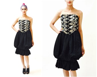 May include: A black strapless dress with a bubble skirt and a sequined bodice. The bodice is a diamond pattern with silver sequins on a black background.