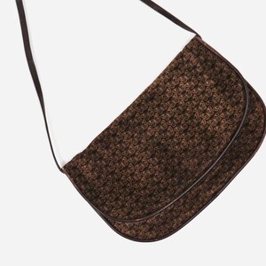 May include: A brown leather shoulder bag with a butterfly pattern. The bag has a long strap and a flap closure.