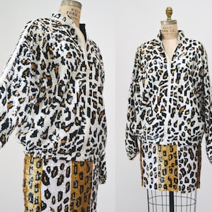 May include: A white and brown leopard print jacket and skirt set. The jacket has a zipper closure and long sleeves. The skirt is a mini skirt with a high waist.