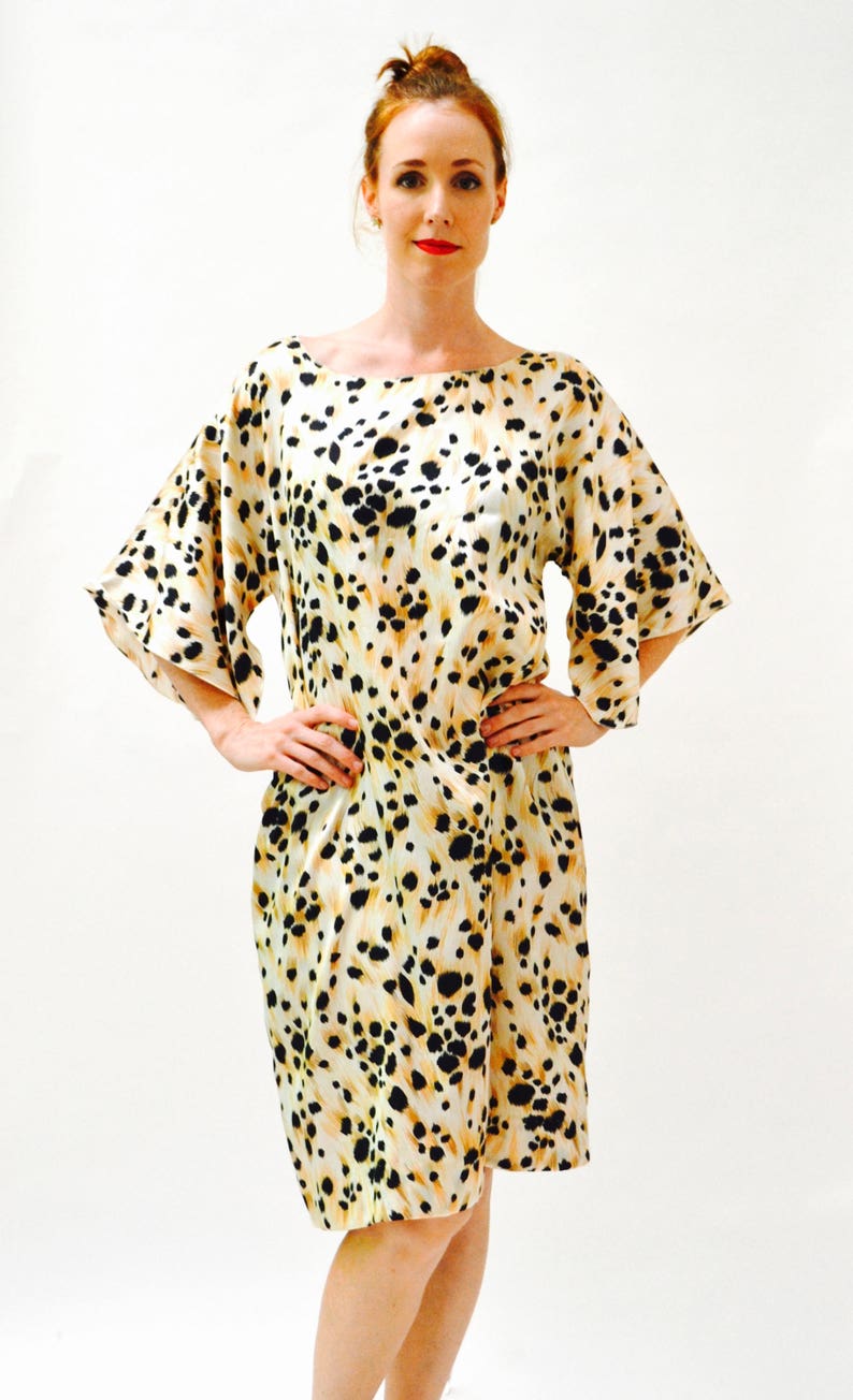 May include: A short-sleeved dress with a leopard print pattern in shades of beige, black, and brown. The dress has a loose fit and a scoop neckline.