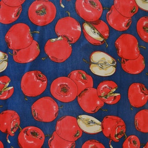May include: A blue fabric with a repeating pattern of red apples. The apples are drawn in a realistic style with some showing a cross-section of the fruit.