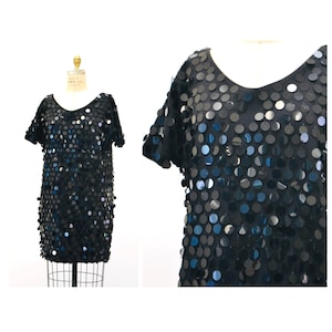 May include: A black short-sleeved dress covered in silver sequins. The sequins are arranged in a circular pattern.