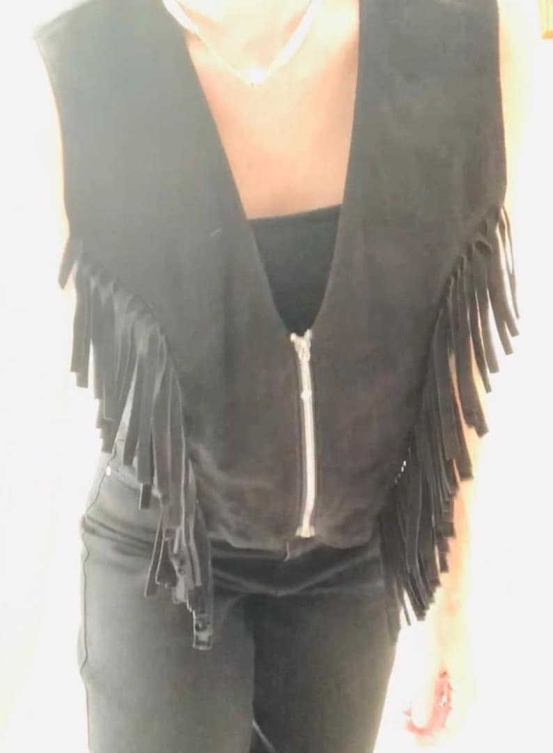 May include: A black suede vest with fringe detailing and a zipper closure.