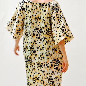 May include: A white dress with a black and brown animal print. The dress has a loose fit and a scoop neck.