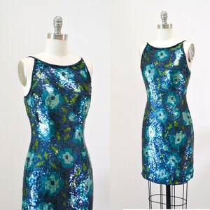 May include: A sleeveless sequined dress with a floral pattern in shades of blue and green. The dress has a scoop neck and a fitted silhouette.