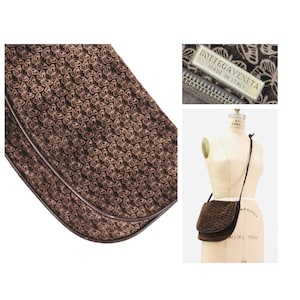 May include: Brown suede shoulder bag with a butterfly pattern and a brown leather trim. The bag has a flap closure and a long adjustable strap. The bag has a label that reads "Bottega Veneta Made in Italy".
