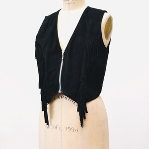 May include: A black suede vest with fringe detailing and a zipper closure.