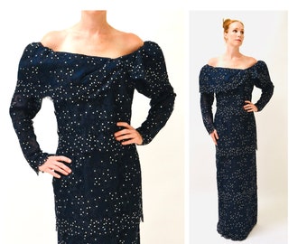 May include: A long, navy blue lace dress with a beaded design. The dress has a scoop neckline and long sleeves with puffed shoulders. The dress is floor-length and has a fitted silhouette.