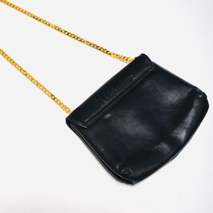 May include: A black leather shoulder bag with a gold chain strap. The bag has a flap closure and the brand name is embossed on the front.