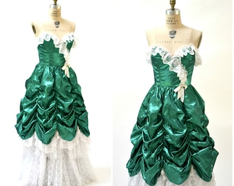 May include: A green and white strapless prom dress with a ruffled skirt and lace trim. The dress is on a mannequin.