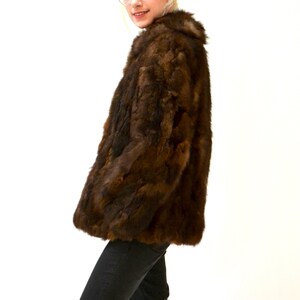 May include: A brown fur jacket with a collar. The jacket is made of rabbit fur.