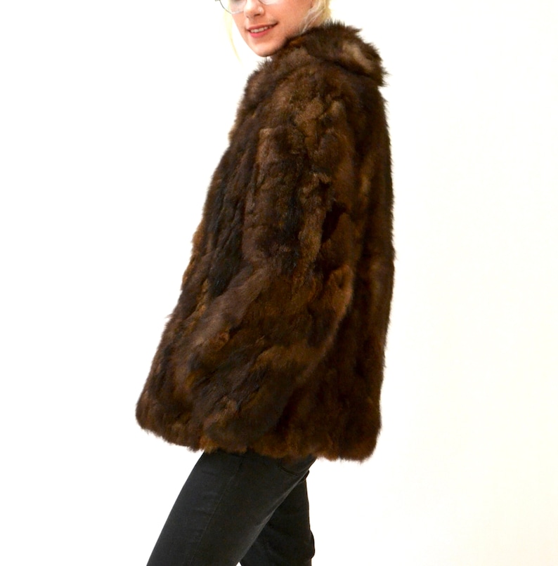 May include: A brown fur jacket with a collar. The jacket is made of rabbit fur.