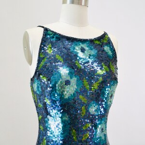 May include: A sleeveless sequined dress with a floral pattern in shades of blue, green, and white. The dress is fitted and has a scoop neckline.