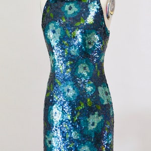 May include: A sleeveless sequined dress with a floral pattern in shades of blue and green.