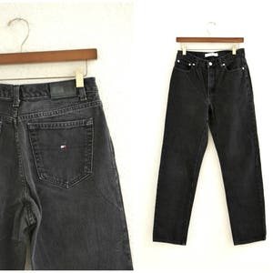 May include: A pair of black denim jeans with a small red, white, and blue logo on the back pocket.