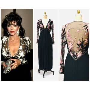 May include: A long black gown with a sheer overlay featuring pink and black star and moon embellishments. The gown has a V-neckline and long sleeves.