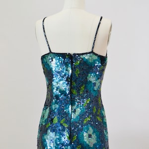 May include: A blue and green sequined dress with a floral pattern. The dress has thin straps and a back zipper.