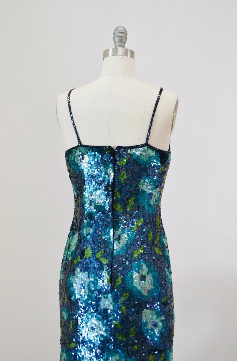 May include: A blue and green sequined dress with a floral pattern. The dress has thin straps and a back zipper.