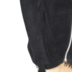 May include: Black suede jacket with a zipper closure and fringe detail on the sleeves.