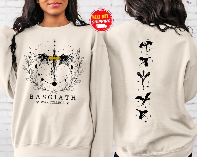 May include: Cream-colored sweatshirt with a black and gold dragon design on the front and back. The front features a dragon with the text "BASGIATH WAR COLLEGE". The back has five black dragon silhouettes.