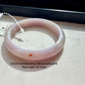 May include: A smooth, translucent light pink and purple bangle bracelet with a small red inclusion. The item features a white plastic security tag attached by a thin cord. Text on the image reads: Good translucency red purple/pink Red sajin no heat.