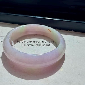 May include: A translucent, full-circle bangle bracelet featuring a smooth, polished surface with blended hues of purple, pink, green, and red. The text 'Purple pink green red sajin Full circle translucent' is printed on the inner surface.
