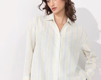 May include: A button-down shirt with vertical stripes in light blue and cream. The long-sleeved shirt has a classic collar and is made of a lightweight fabric. The shirt is a relaxed fit.